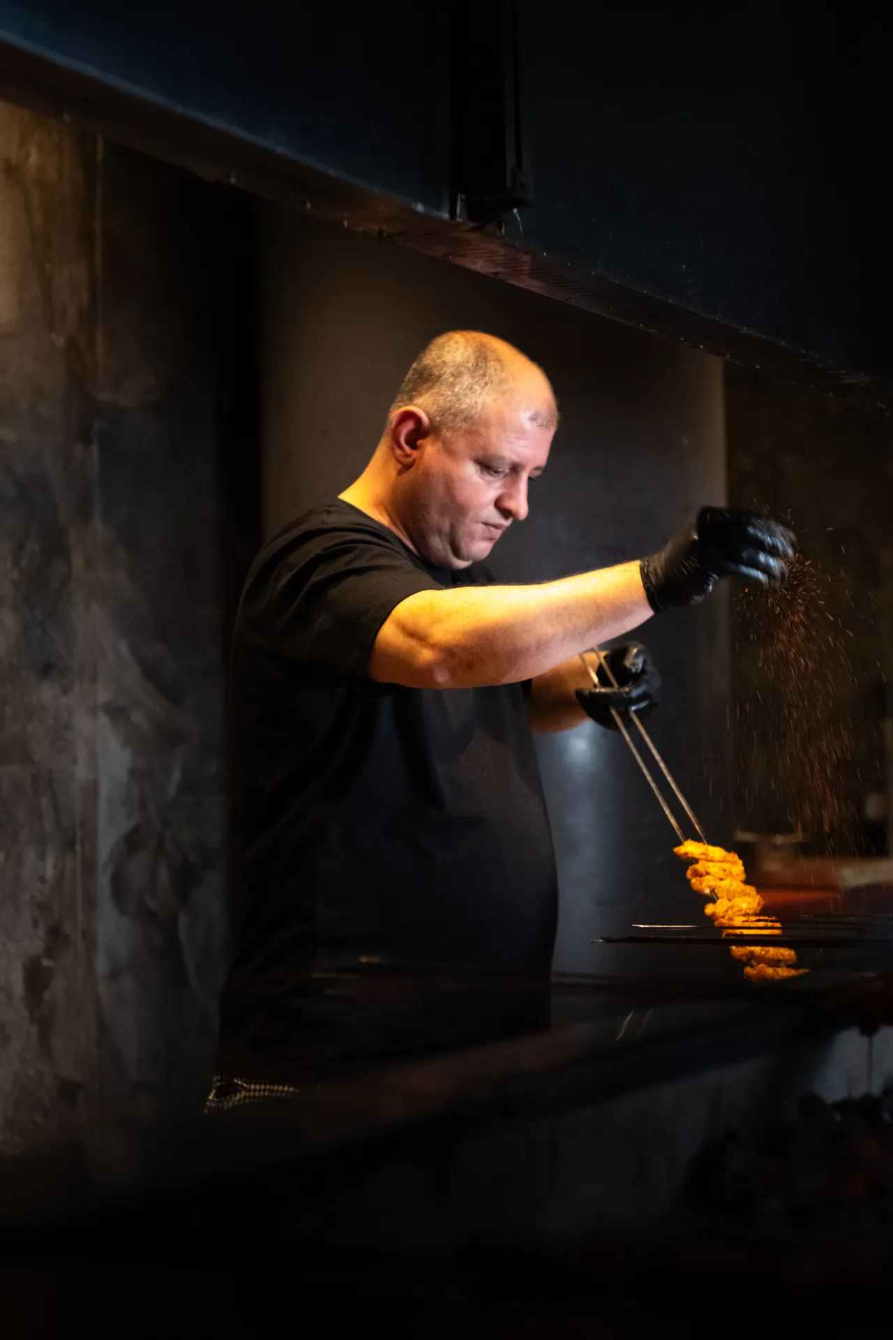 A cook working the grill in a shaft of light.
